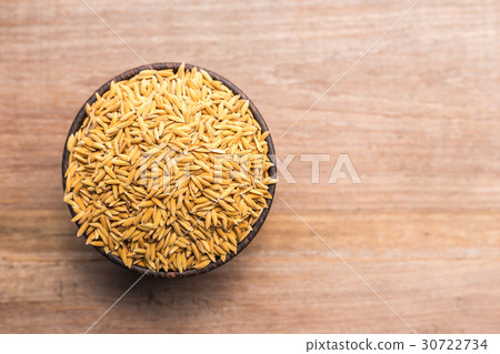 Thai yellow paddy rice in wooden bowl put on wooden plank background 30722734