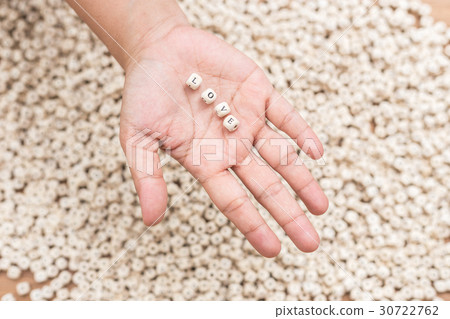 LOVE word in woman hand above pattern of white english alphabet letters LOVE word in woman hand above pattern of white english alphabet letters 30722762