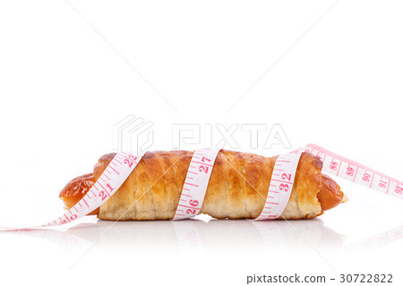 Sausage bread and measurement tape. Studio shot isolated on white. Junk food, obesity or food healthy concept Sausage bread and measurement tape. Studio shot isolated on white. Junk food, obesity or food healthy concept 30722822