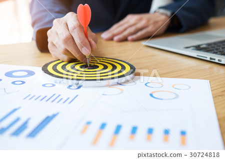 Business Man hand holding a target with darts hitting the center Business Man hand holding a target with darts hitting the center 30724818