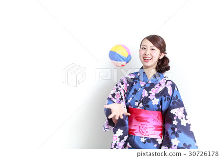 A young lady wearing a yukata playing with a paper breeze 30726178