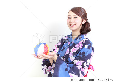 A young lady wearing a yukata playing with a paper breeze 30726179