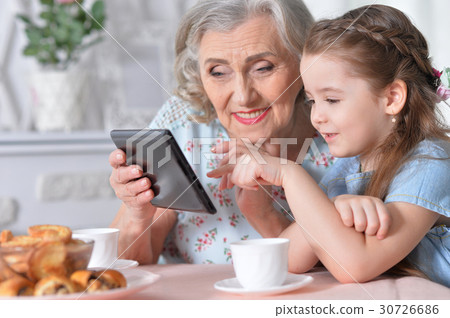 Grandmother with granddaughter playing in a tablet 30726686