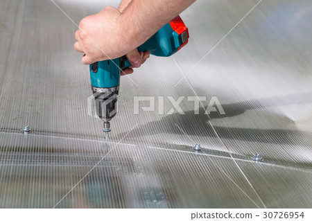 Worker screwing screw into polycarbonate Worker screwing screw into polycarbonate 30726954