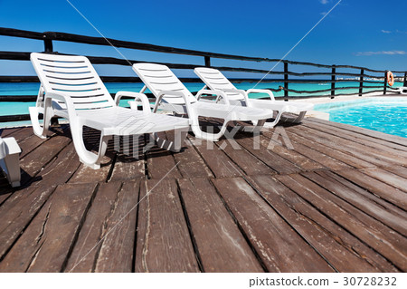 Luxury sunbeds on wooden floor near swimming pool Luxury sunbeds on wooden floor near swimming pool 30728232