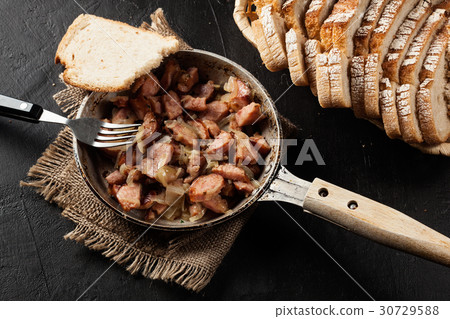 Pieces of sausage fried with onions 30729588