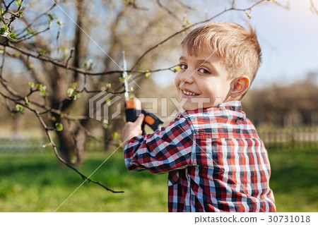 Charming child looking at camera while pruning 30731018