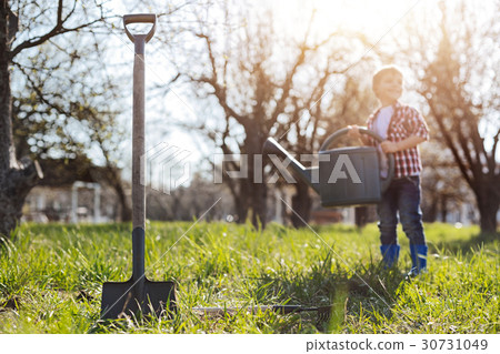Charming kid holding watering can in garden 30731049