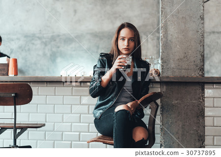 Beautiful girl in a black jacket in a cafe Beautiful girl in a black jacket in a cafe 30737895