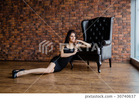 Tall slender brunette next to a armchair Tall slender brunette next to a armchair 30740637