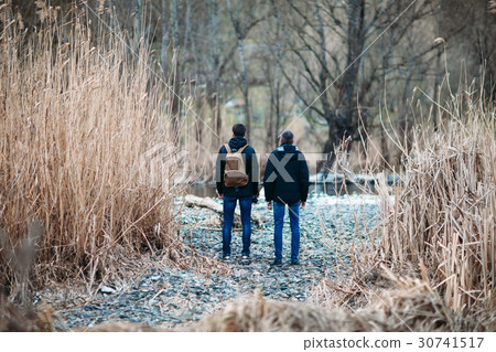 Back view of men standing on road in forest 30741517