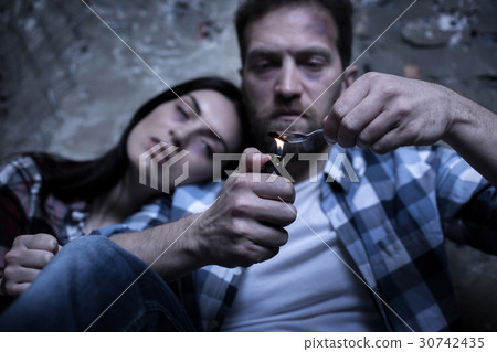 Tired addicted couple heating heroin on the spoon Tired addicted couple heating heroin on the spoon 30742435