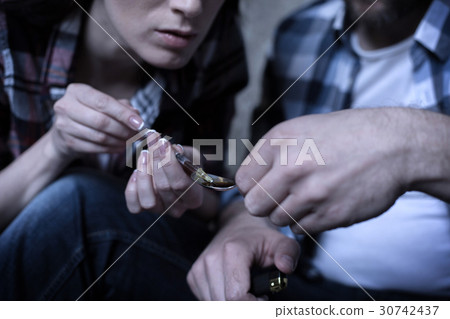 Stoned addicts heating heroine over the flame in 30742437
