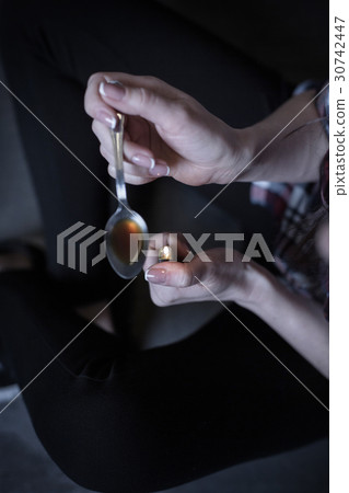 Deeply obsessed woman heating drug dose in the 30742447