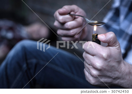 Experienced freak heating heroin on the spoon in 30742450