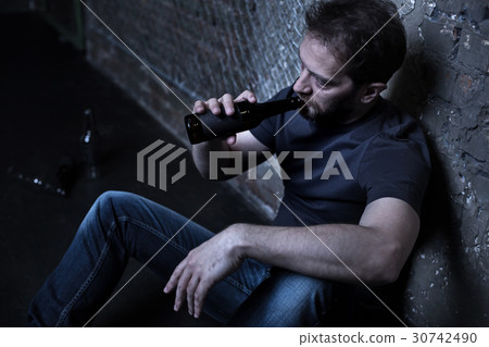 Thoughtful addict drinking alcohol in the dark Thoughtful addict drinking alcohol in the dark 30742490