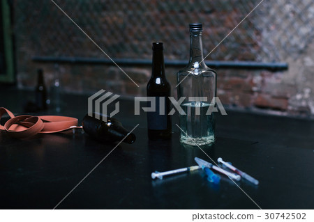 Bottles full of alcohol and syringes lying on the Bottles full of alcohol and syringes lying on the 30742502