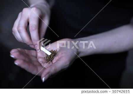 Female drug user holding marijuana cigarette Female drug user holding marijuana cigarette 30742655