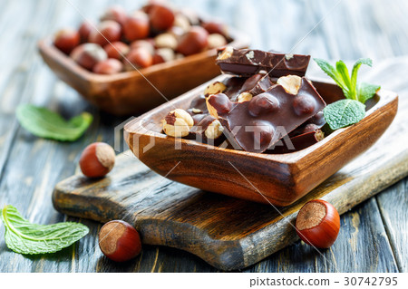 Chocolate with hazelnuts in a wooden bowl. 30742795