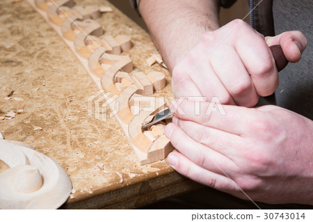 woodcarver creates a furniture ornament.  30743014