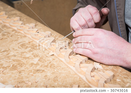 woodcarver creates a furniture ornament.  30743016