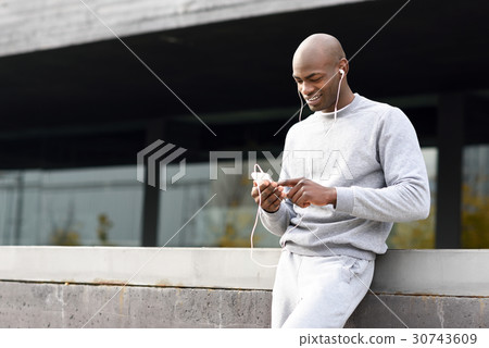 Attractive black man listening to music with headphones in urban Attractive black man listening to music with headphones in urban 30743609