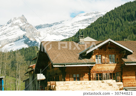 Lovely Swiss chalet with mountains in background Lovely Swiss chalet with mountains in background 30744821
