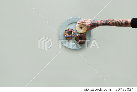 Hand with tattoo reaching for donut Hand with tattoo reaching for donut 30753824