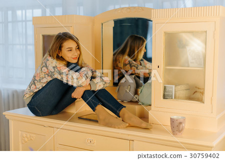 The smiling teenager is hugging her knees while The smiling teenager is hugging her knees while 30759402
