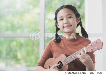 Beautiful Asian girl playing ukulele Beautiful Asian girl playing ukulele 30761586