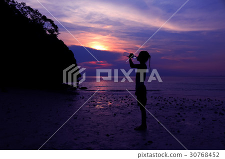 Asian girl drinking water on the beach. Asian girl drinking water on the beach. 30768452