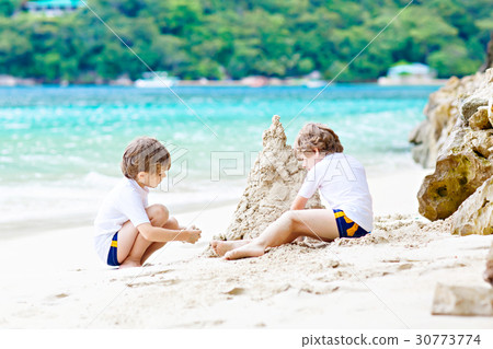 Two kid boys building sand castle on tropical 30773774