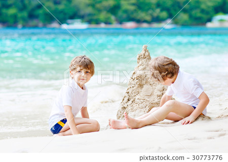 Two kid boys building sand castle on tropical 30773776