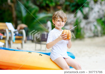 Little kid boy drinking coconut juice on tropical 30773786