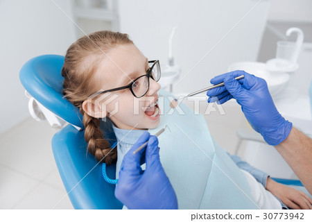 Cheerful young lady sitting in dentists chair 30773942