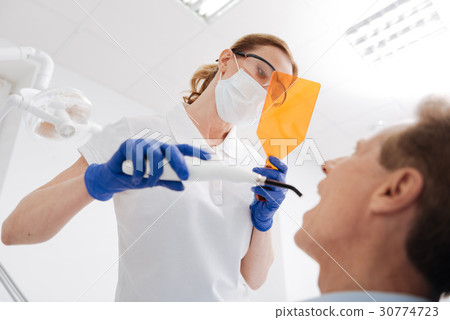 Precise dedicated dentist looking through special 30774723