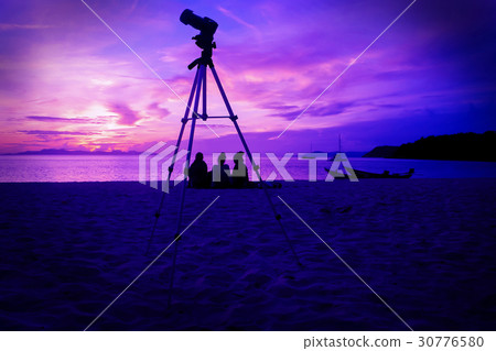 Camera and tripod with three girls on the beach. 30776580