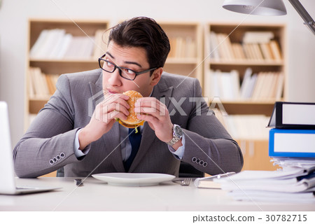 Hungry funny businessman eating junk food sandwich Hungry funny businessman eating junk food sandwich 30782715