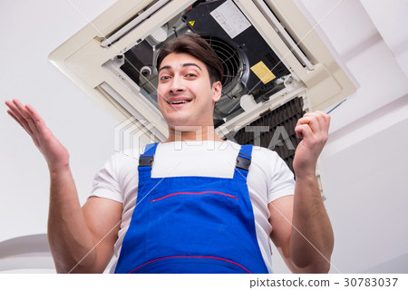 Worker repairing ceiling air conditioning unit 30783037