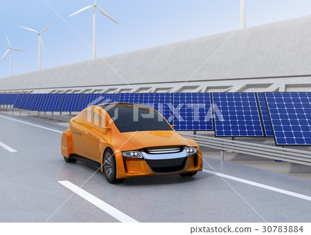 An orange electric car running on a highway. Sunlight and wind power generation facilities are installed on the road side 30783884