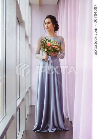 Beautiful woman in a plum dress posing with a Beautiful woman in a plum dress posing with a 30784087