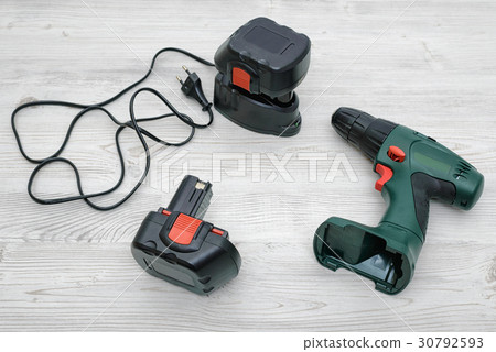 A green cordless drill, a spare battery and a A green cordless drill, a spare battery and a 30792593