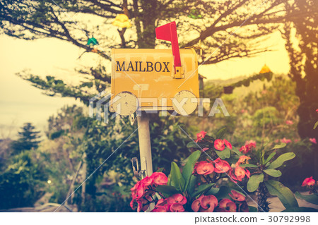 yellow stained metal mailbox has red flag raise up 30792998