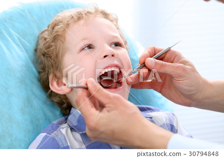 Close up of boy having his teeth examined by a 30794848