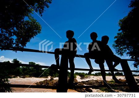 Silhouette Little boy sitting on a fence 30797731