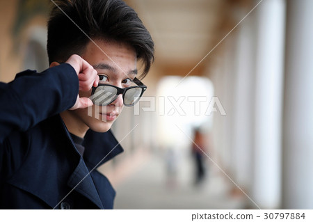 Asian young man in a coat on the street Asian young man in a coat on the street 30797884