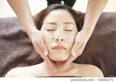 two hands are holding the face of a woman. 30800275