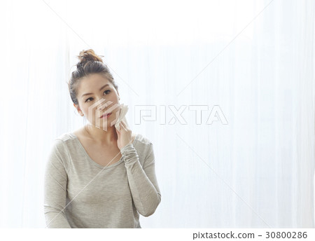 A woman is cleaning sweat after doing yoga exercise. A woman is cleaning sweat after doing yoga exercise. 30800286