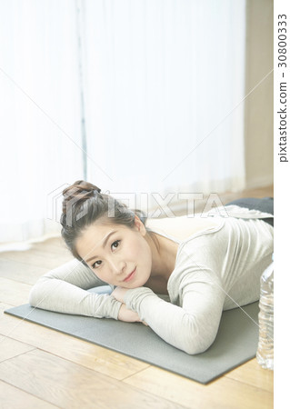 A woman is lying down to relax after doing yoga exercise. A woman is lying down to relax after doing yoga exercise. 30800333