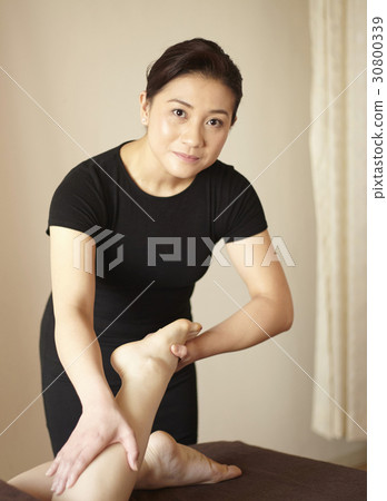 The therapist is stretching leg to massage. The therapist is stretching leg to massage. 30800339